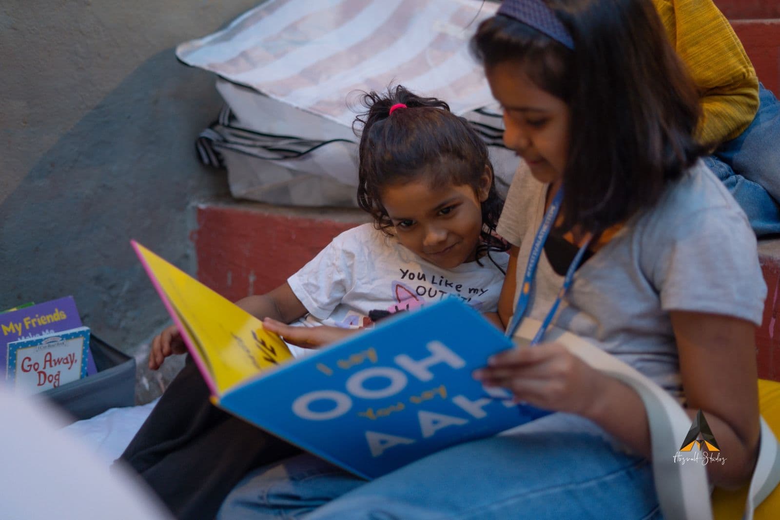 A volunteer reading a bright blue picture book with a young girl