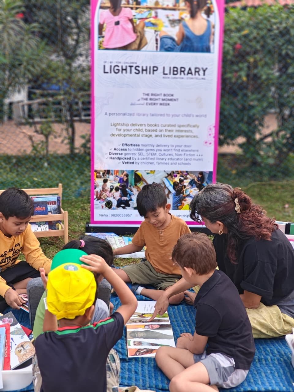 Neha reading aloud to a circle of children at a Lightship pop-up stall